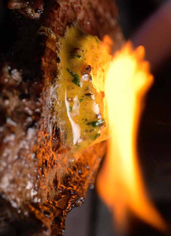 Earle’s compound butter being flamed over a charcoal-grilled steak